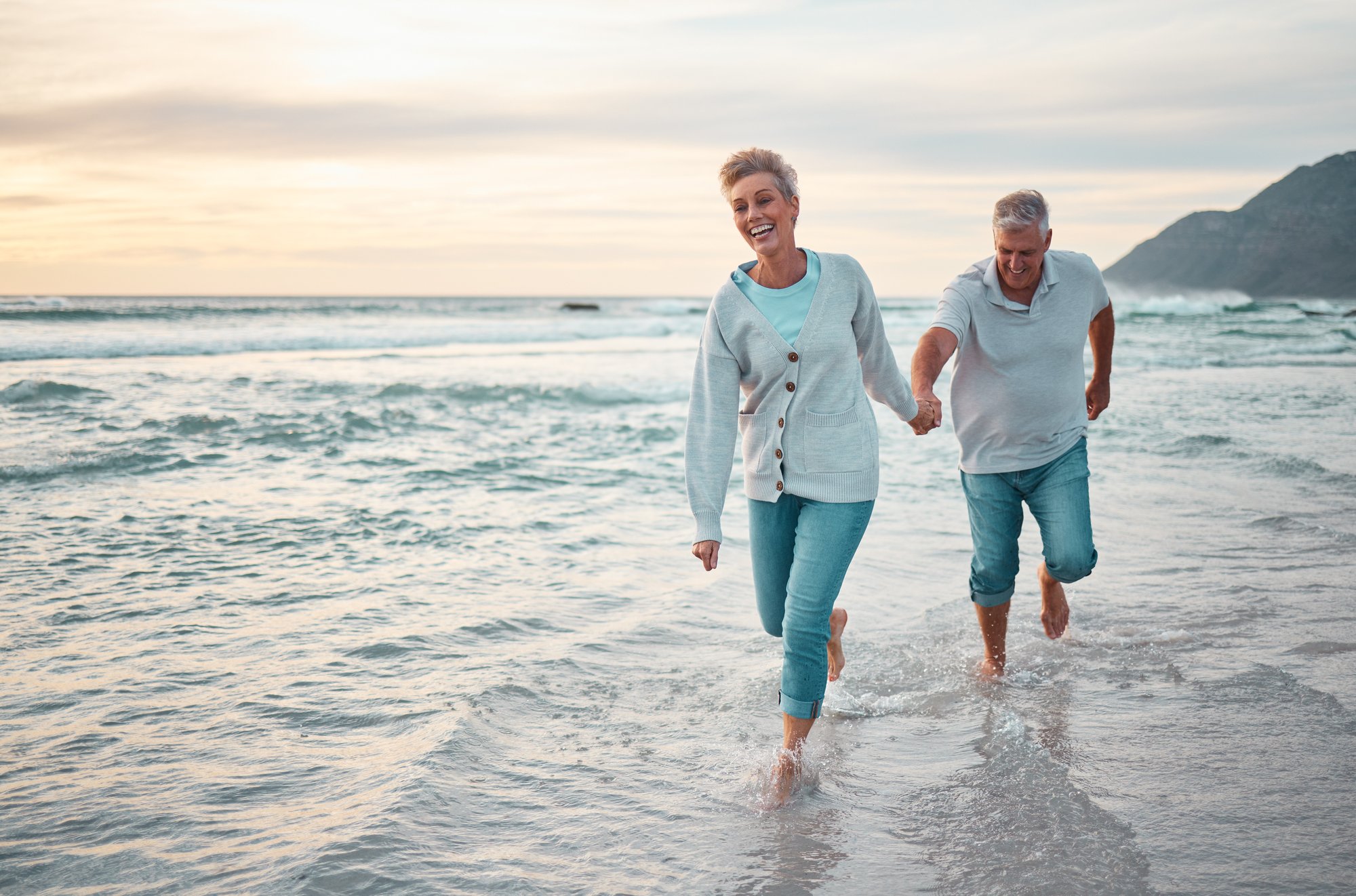 beach-walking-senior-couple-holding-hands-support-love-care-with-outdoor-wellness-retirement-holiday-lifestyle-with-sunset-sky-elderly-people-running-together-sea-ocean-water